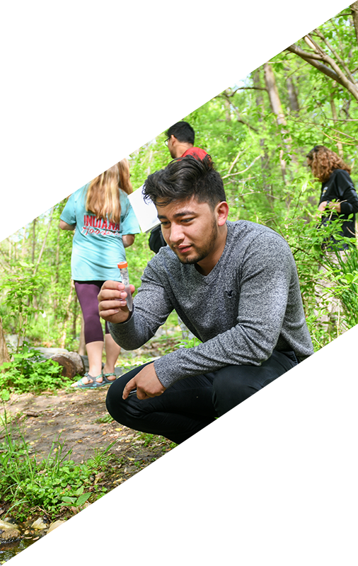 Student holding test tube in the forest
