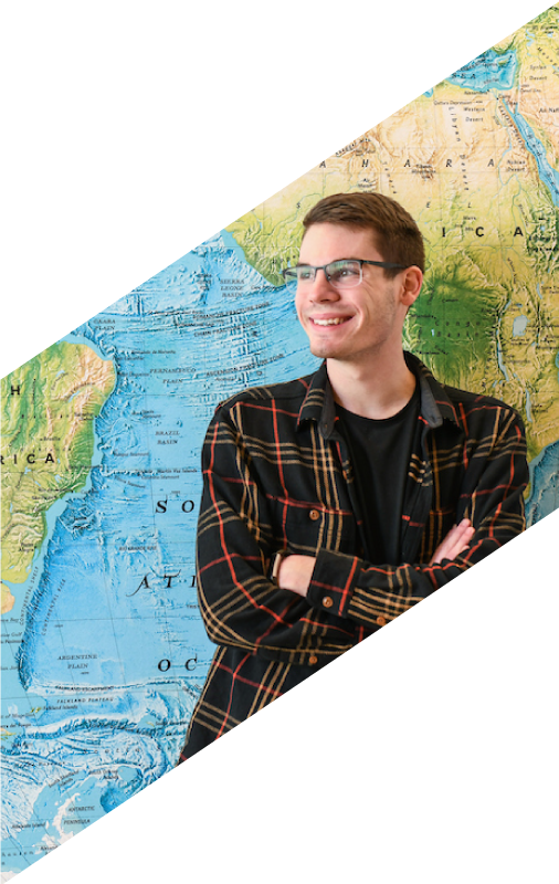 Student smiling in front of world map