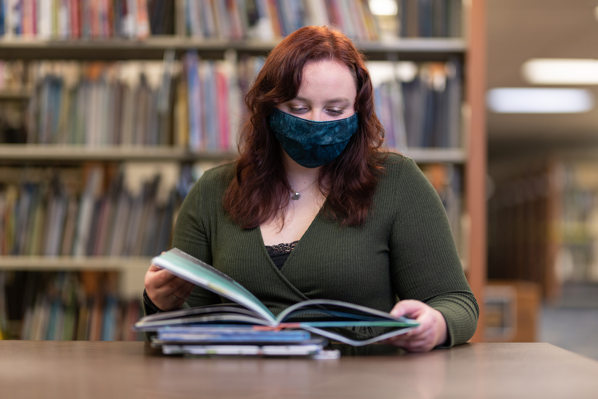Student with mask reading in library
